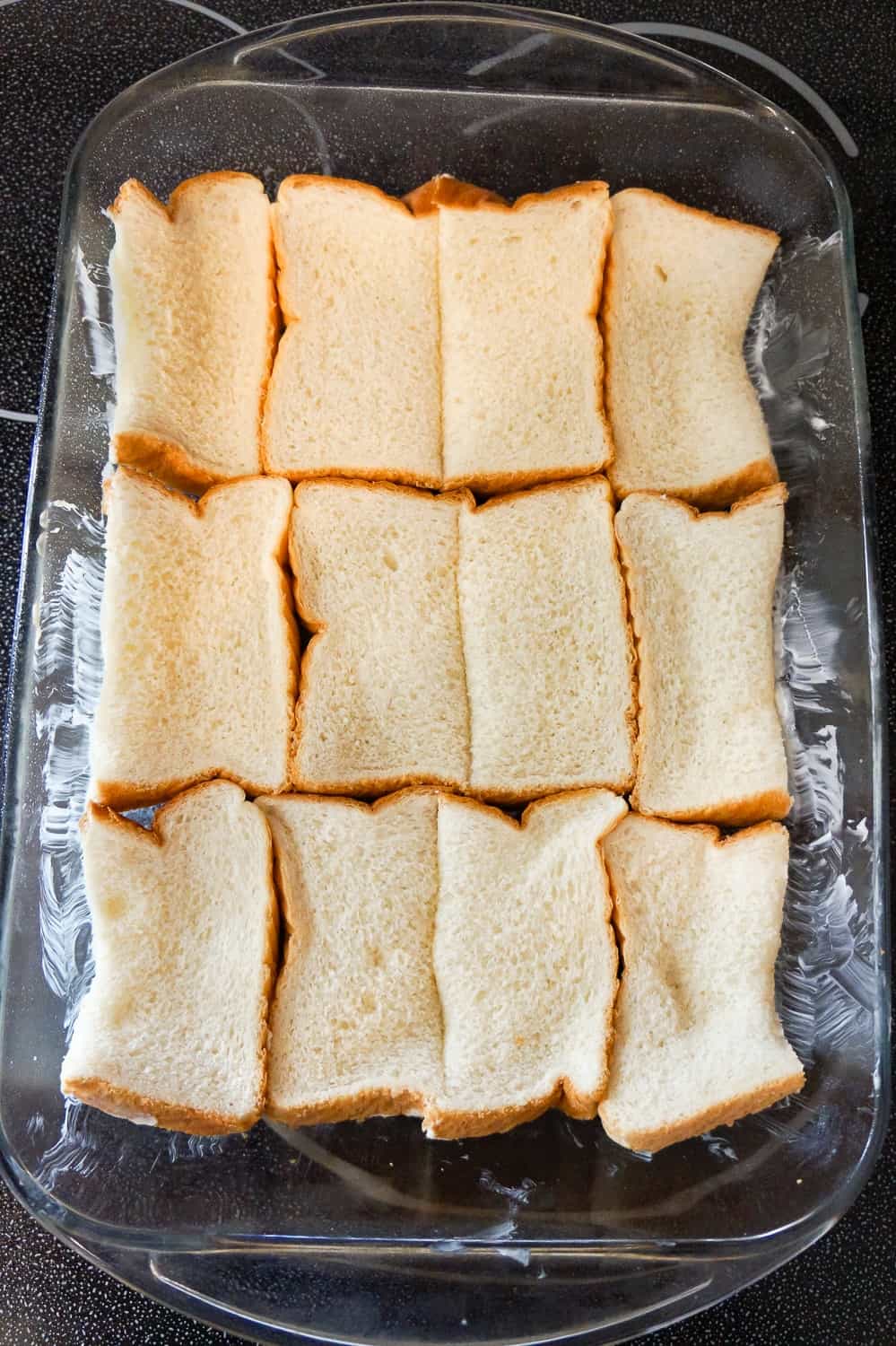 pieces of bread in the bottom of a glass baking dish