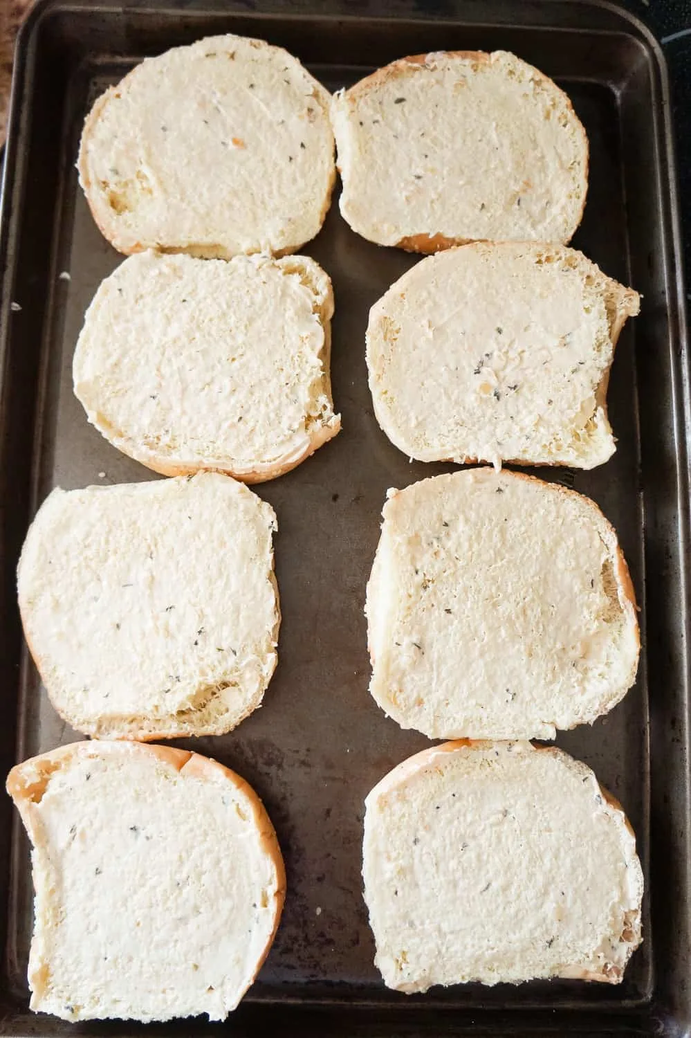 hamburger buns spread with garlic margarine and laying on a baking sheet