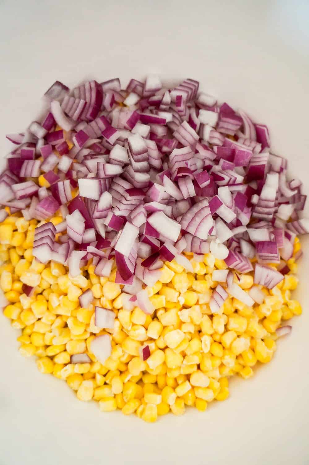 diced red onions and frozen corn in a mixing bowl