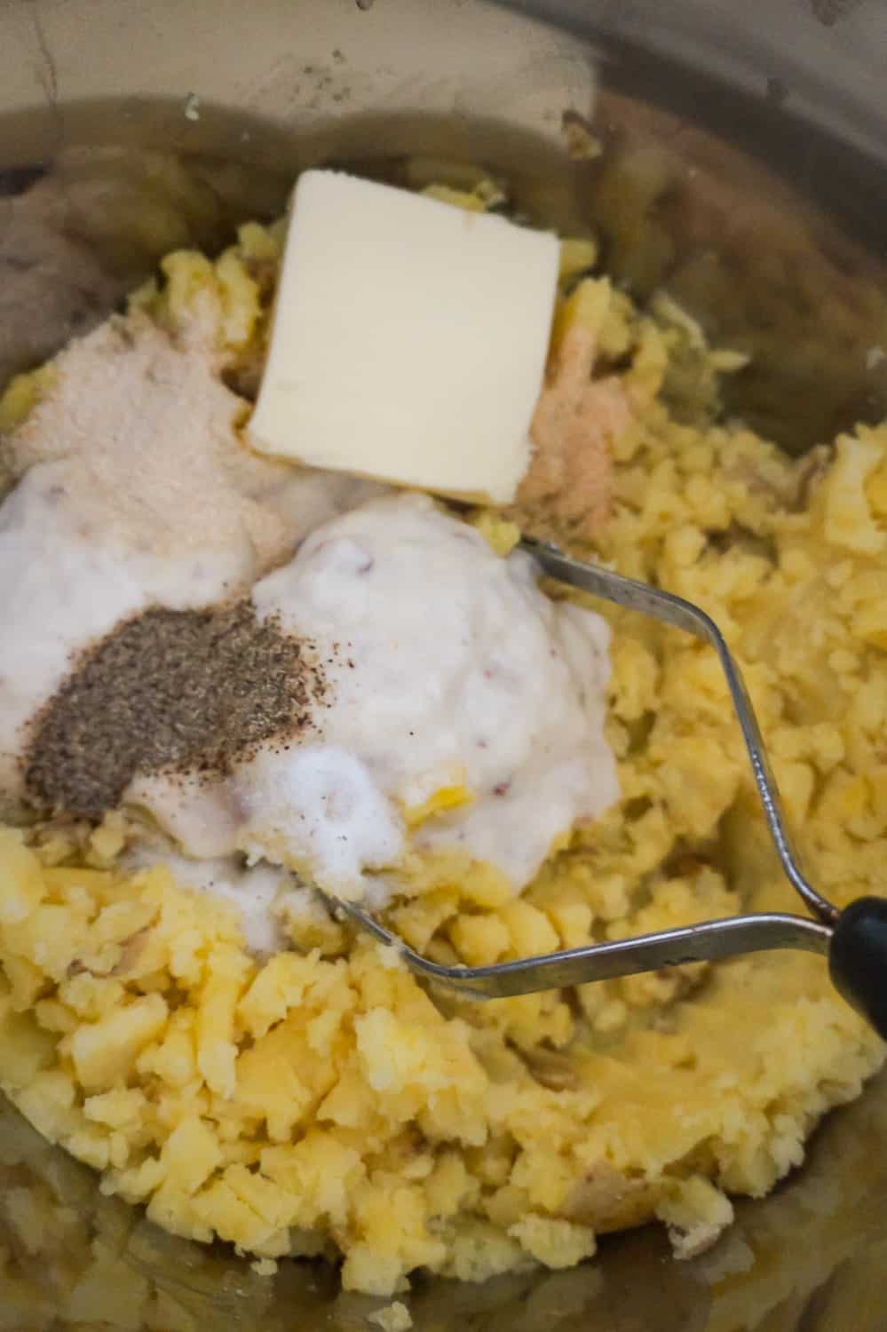 butter, cream of bacon soup and seasonings on top of mashed potatoes in an Instant Pot