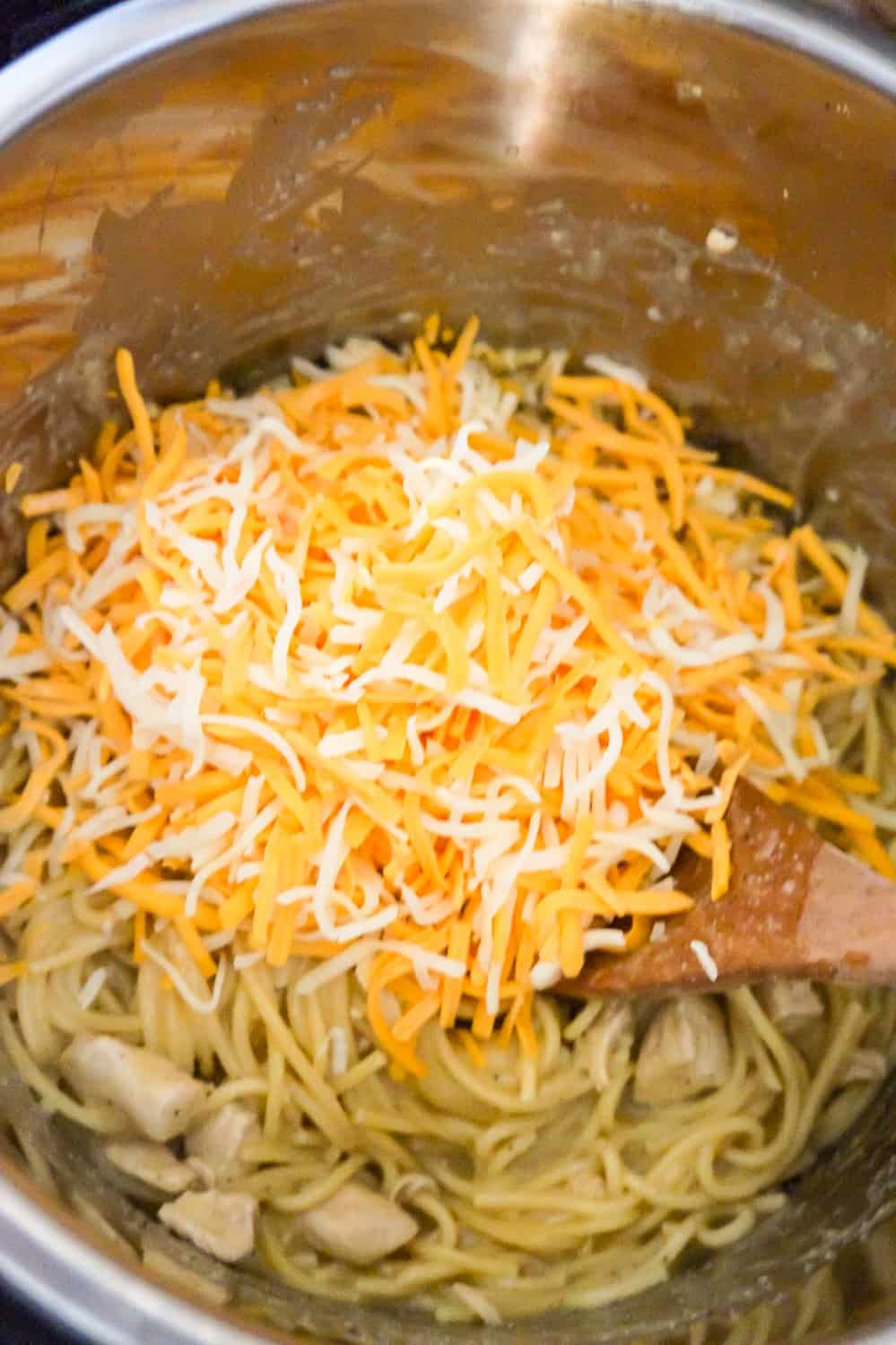shredded mozzarella and cheddar on top of spaghetti in an Instant Pot