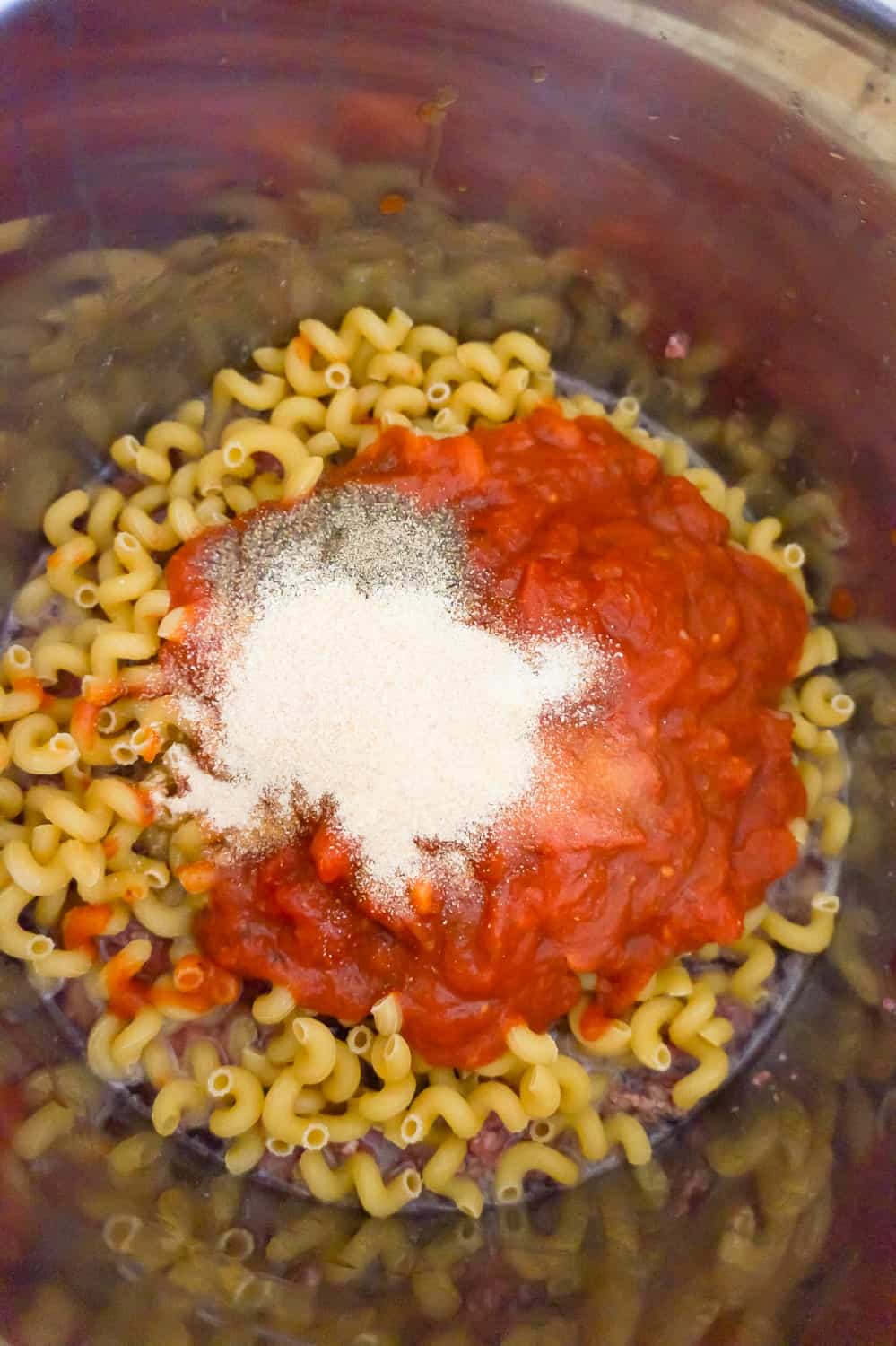 marinara and seasonings on top of cavatappi pasta in an Instant Pot