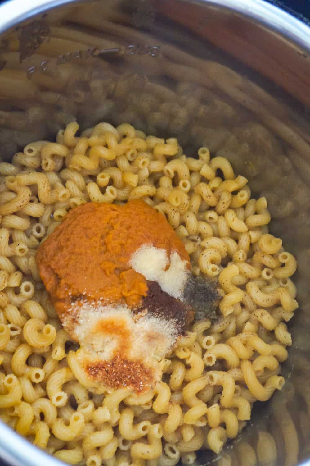 canned pumpkin and spices on top of pasta after cooking in an Instant Pot