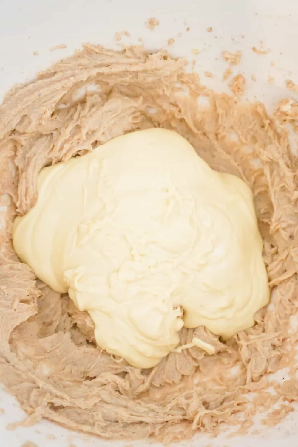 melted white chocolate on top of pumpkin spice cream cheese mixture in a mixing bowl