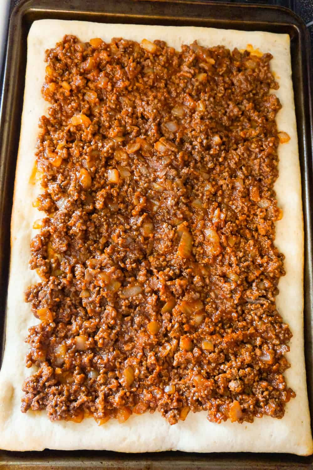 sloppy joe ground beef mixture spread on top of rectangular pizza crust