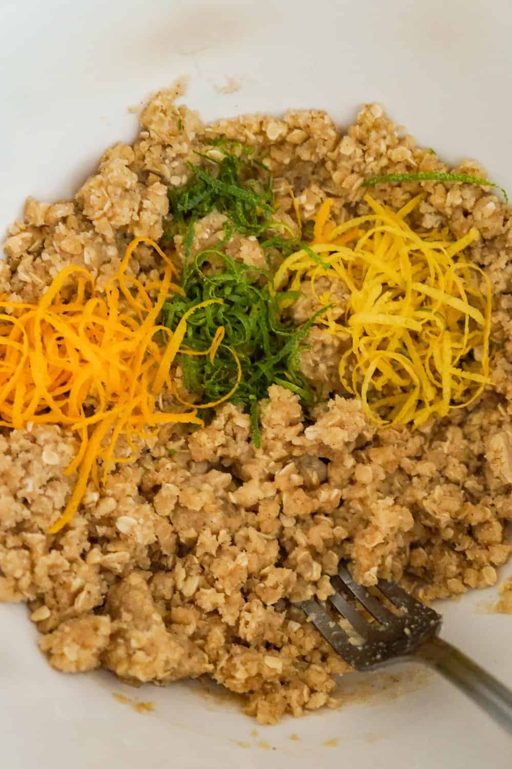 lemon zest, lime zest and orange zest on top of flour and oat mixture in a mixing bowl