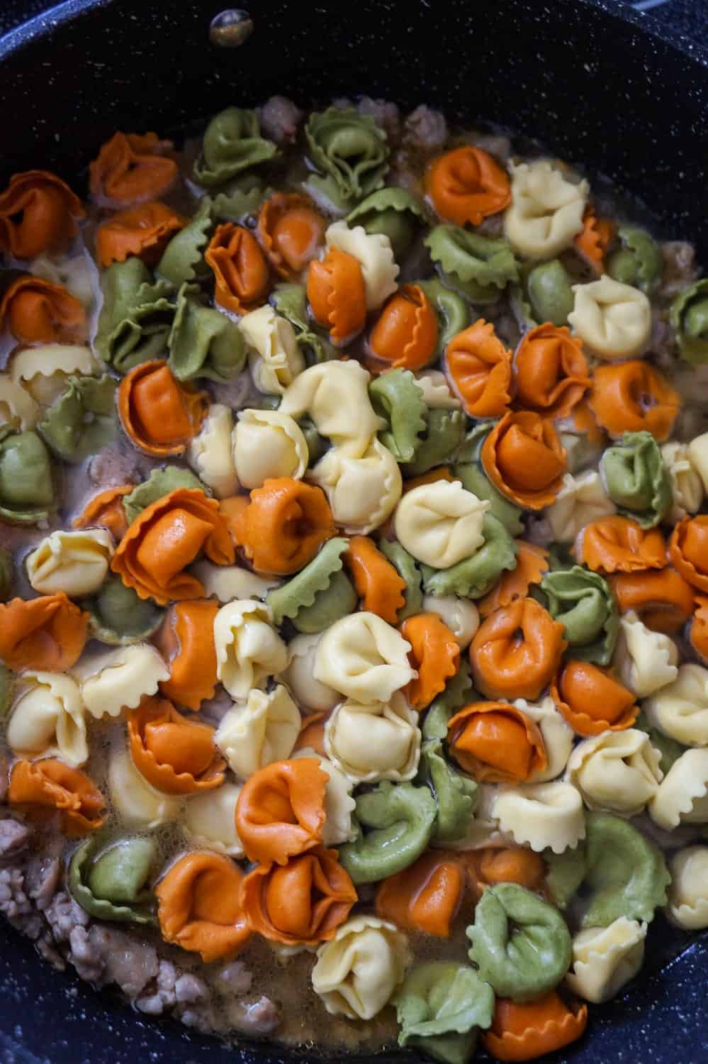 tortellini in a pan with sausage meat