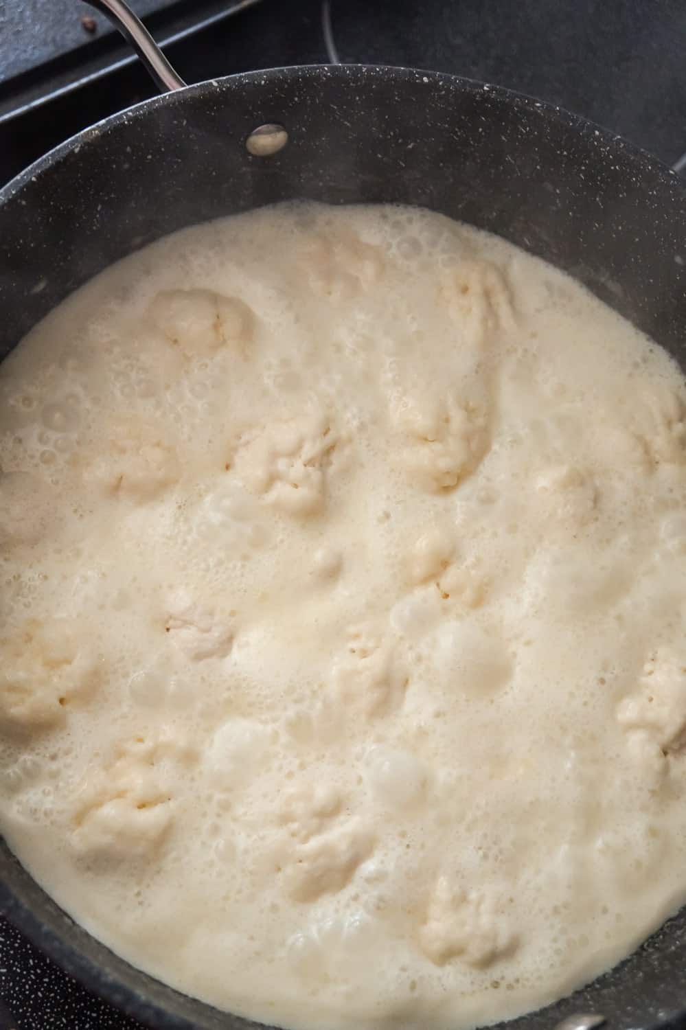 Bisquick dumplings added to creamy chicken mixture in a pot