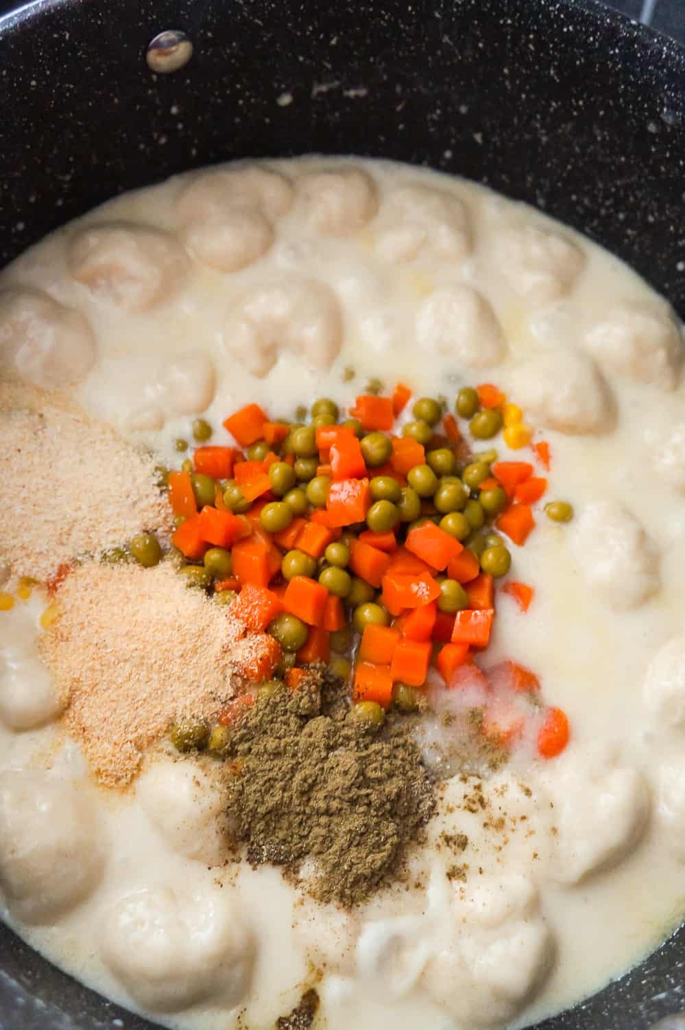 peas, carrots, salt, pepper and onion powder on top of cream chicken and dumplings