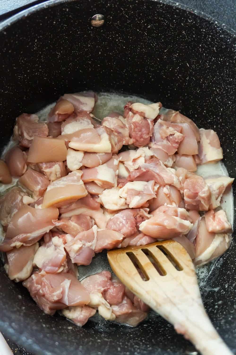 raw chicken thigh pieces in melted butter in a large pot