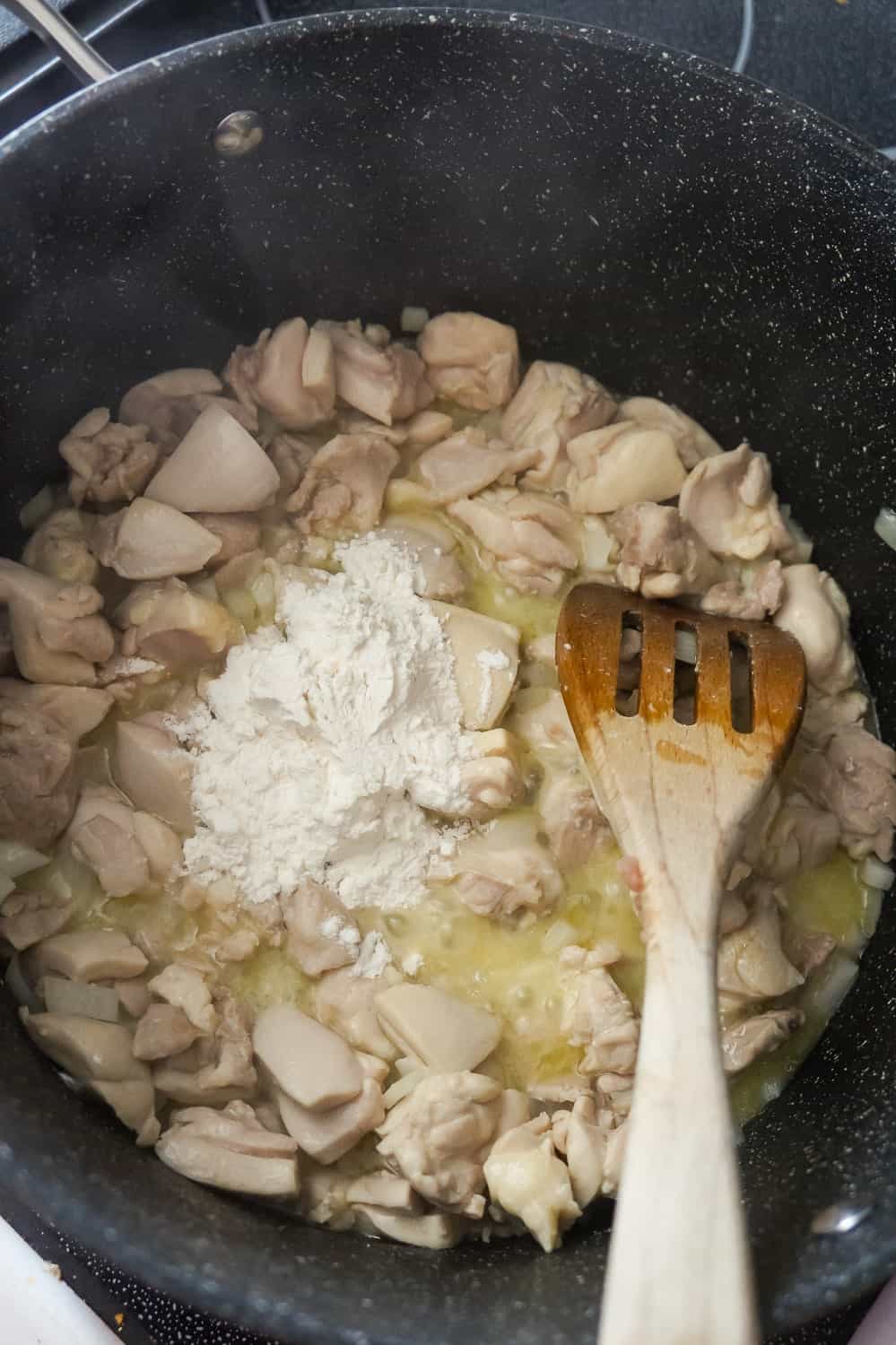 all purpose flour on top of chicken pieces, diced onions and melted butter in a large pot