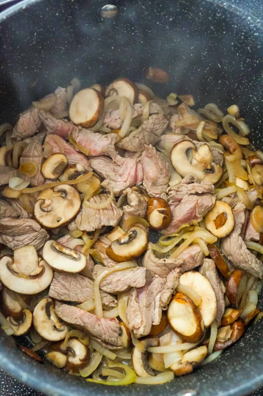 steak strips, sliced mushrooms and sliced onions in a large pan
