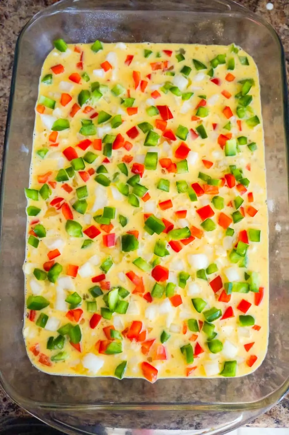 diced green peppers, red peppers and onions on top of egg casserole before baking