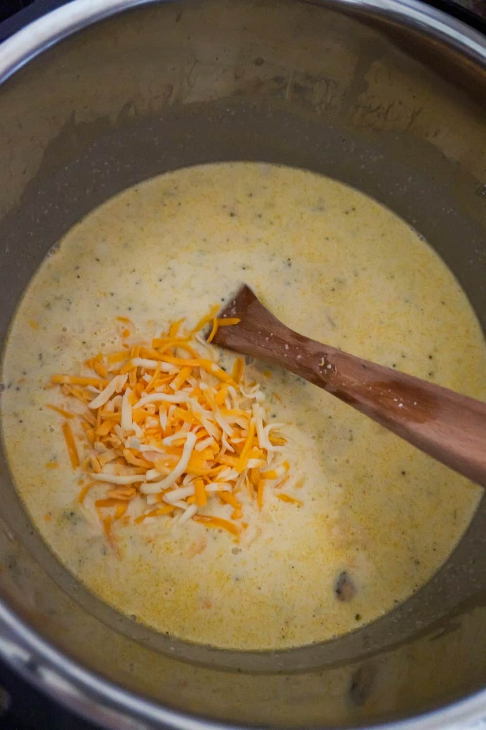shredded cheddar cheese on top of broccoli soup in an Instant Pot