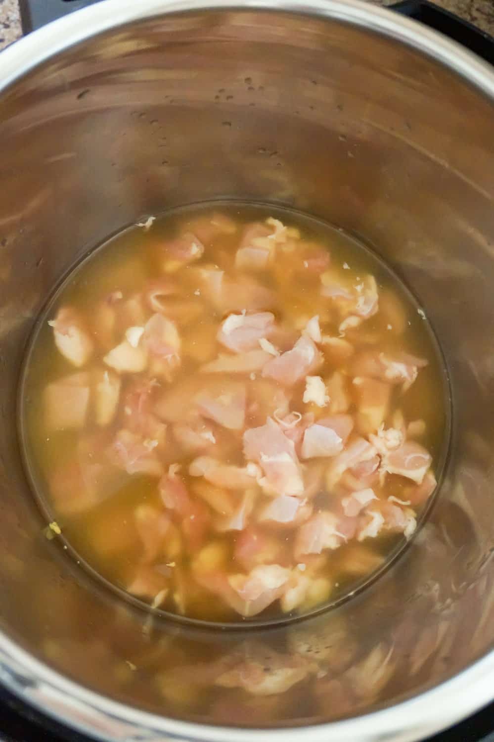 chunks of raw chicken in chicken broth in an Instant Pot