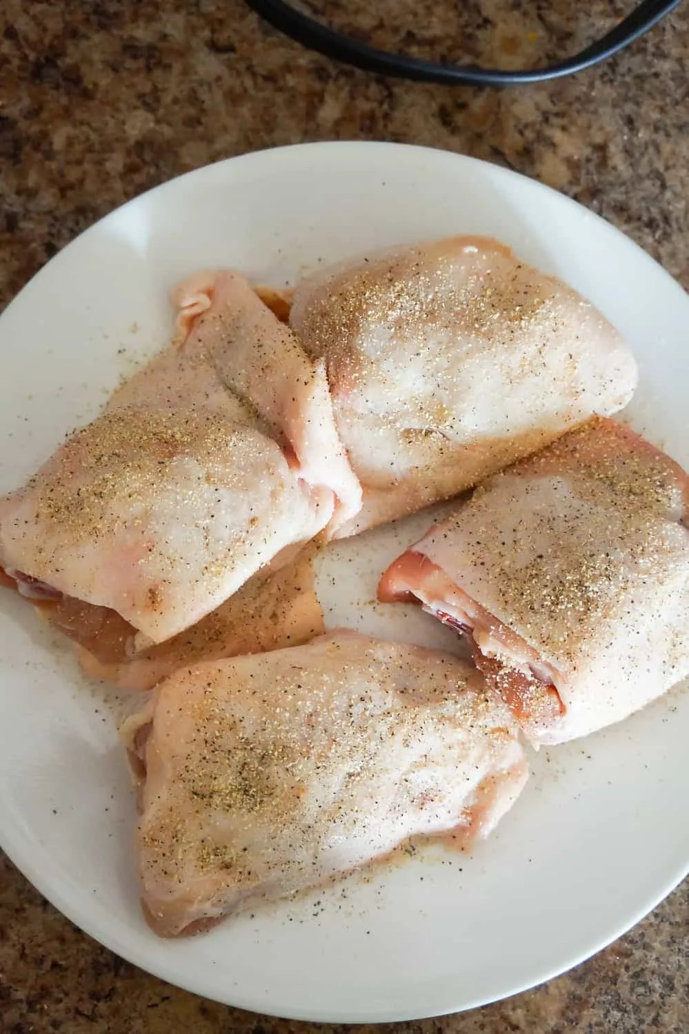 seasoned raw bone in chicken thighs with skin on a plate