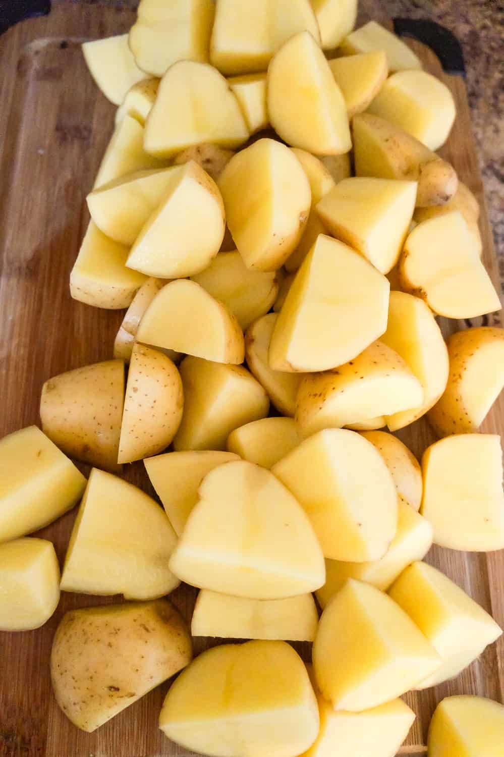 raw potato quarters on a cutting board