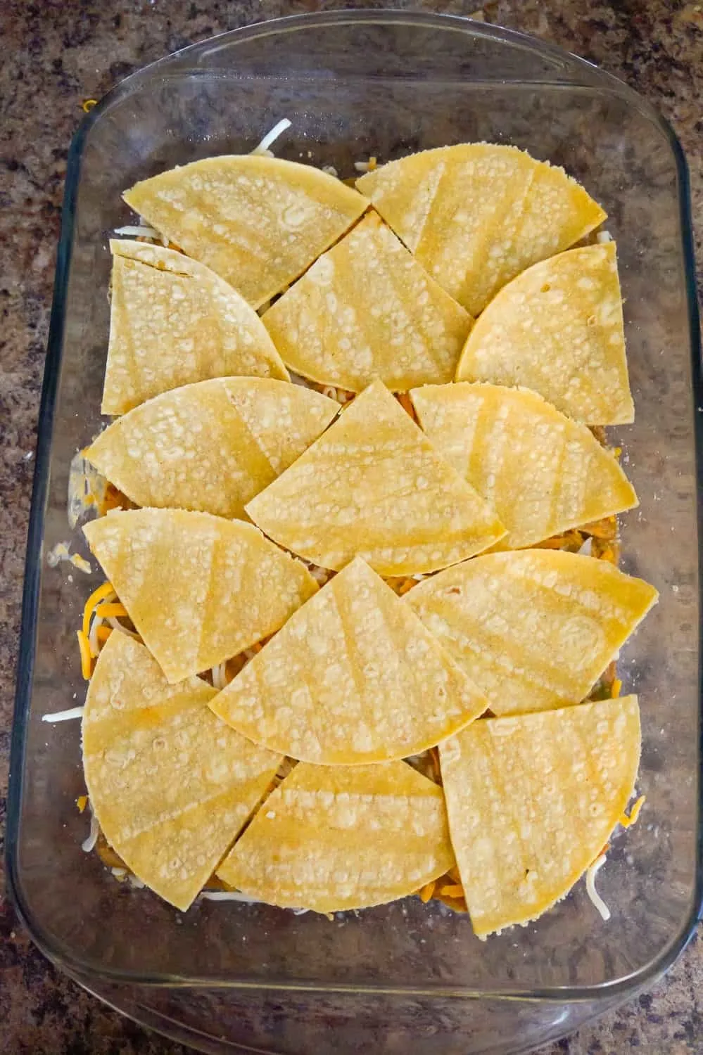 corn tortilla quarters on top of chicken mixture in a baking dish