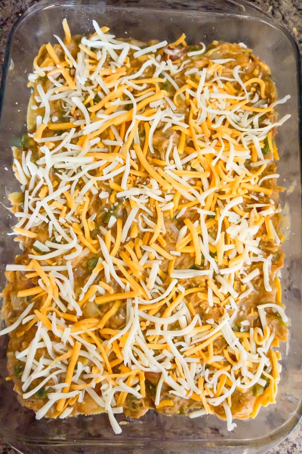 shredded cheese on top of chicken mixture in a baking dish