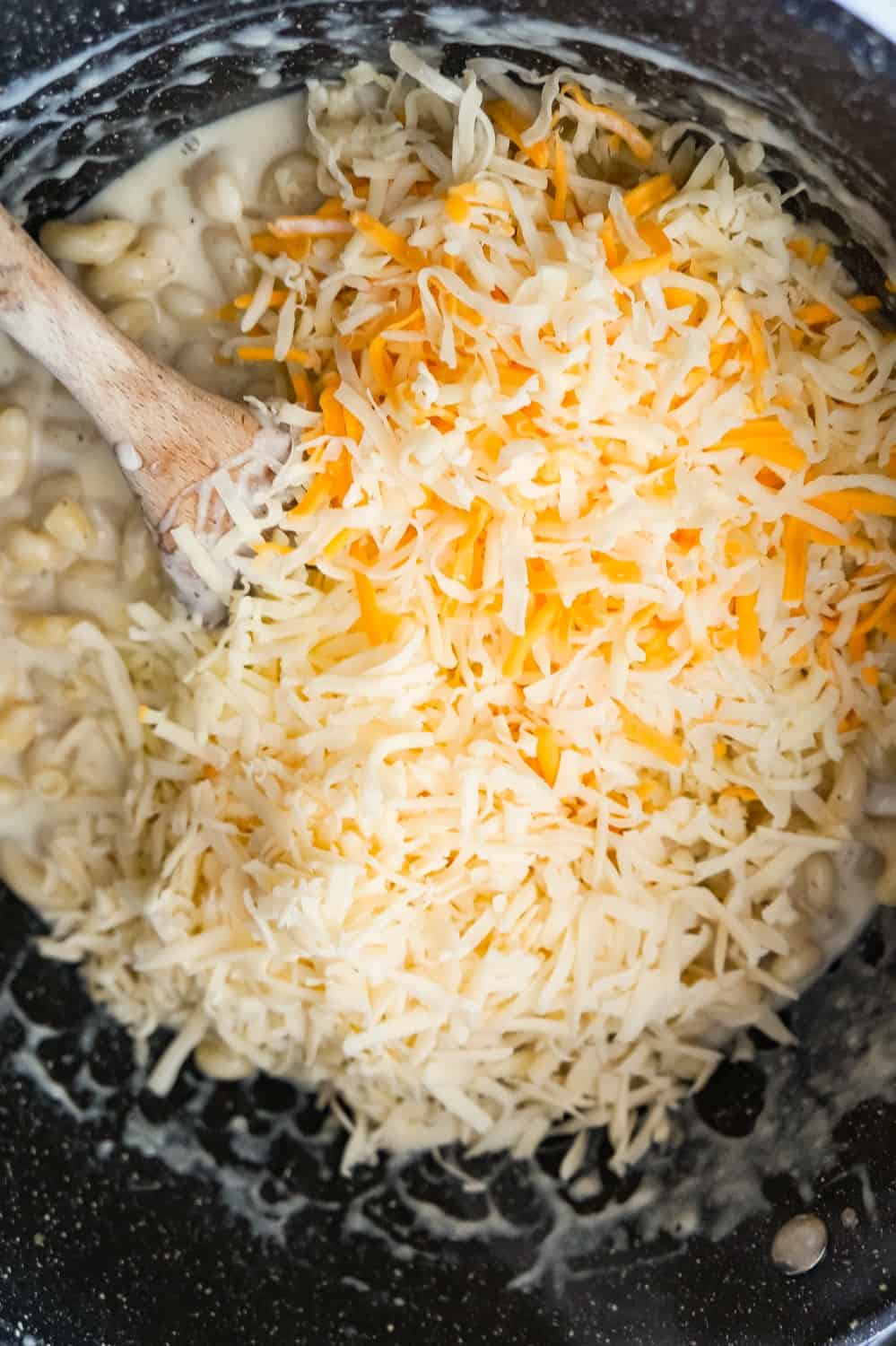 shredded mozzarella, cheddar and Swiss cheese on top of creamy pasta in a large pot