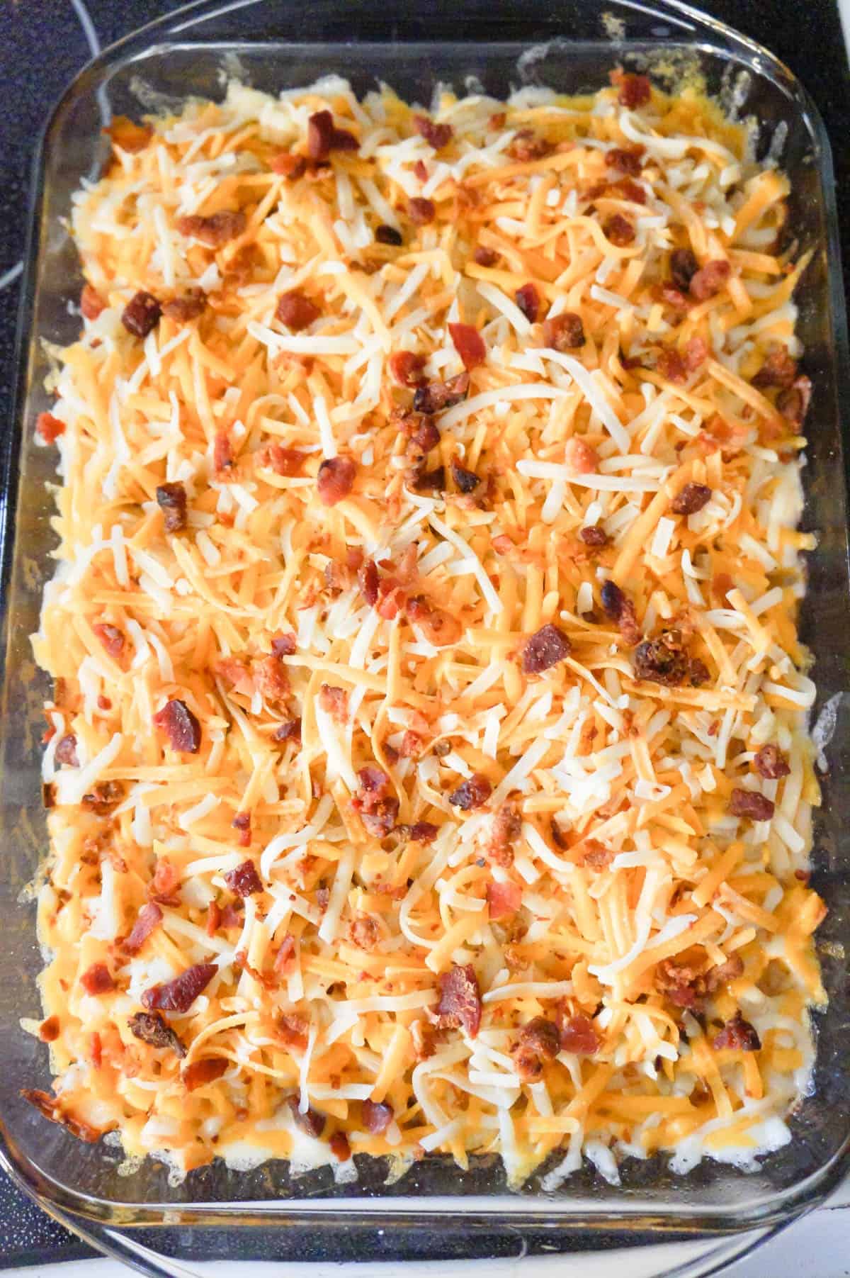 shredded cheddar cheese and crumbled bacon on top of hash brown casserole