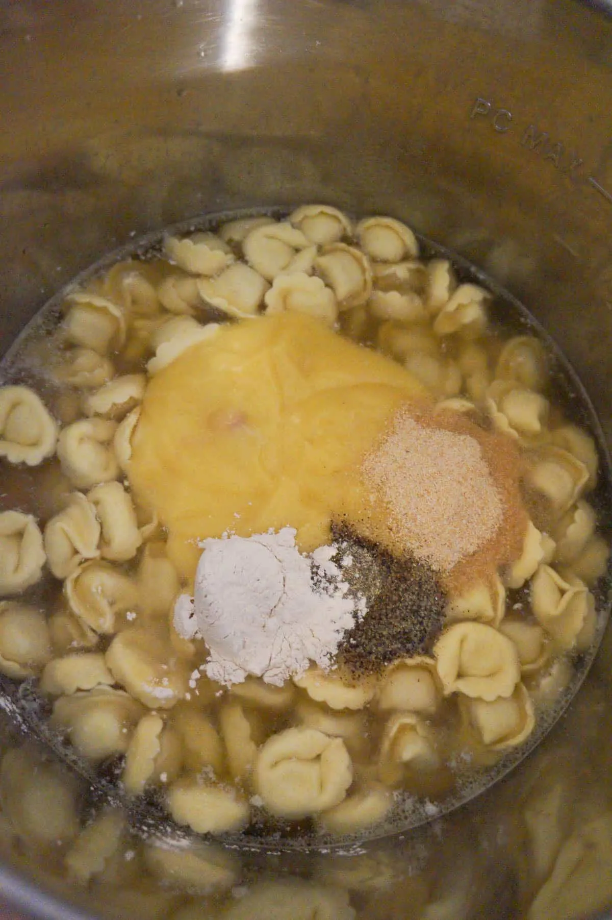 cream of chicken soup and spices on top of tortellini in an Instant Pot