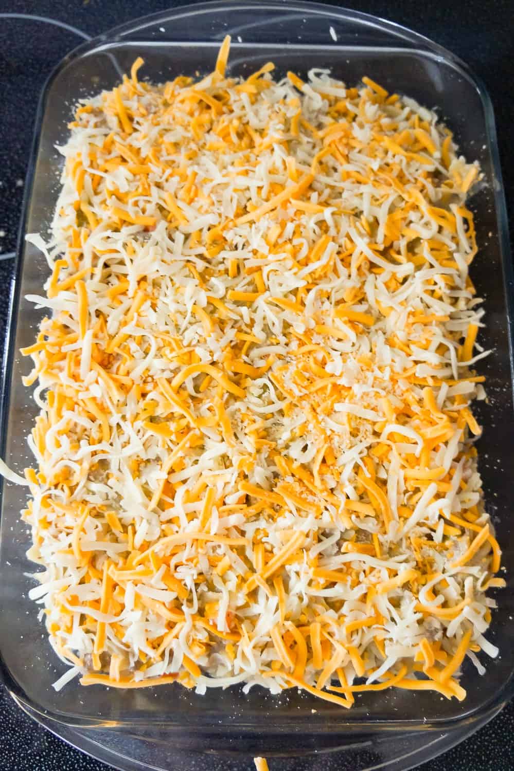 shredded cheese on top of hamburger noodle casserole before baking