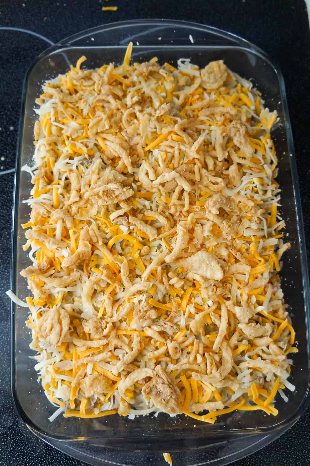 French's fried onions and shredded cheese on top of hamburger noodle casserole before baking
