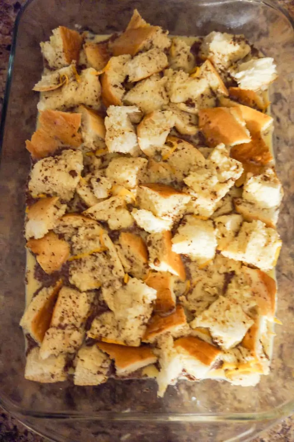 egg and cinnamon mixture poured over bread cubes in a baking dish