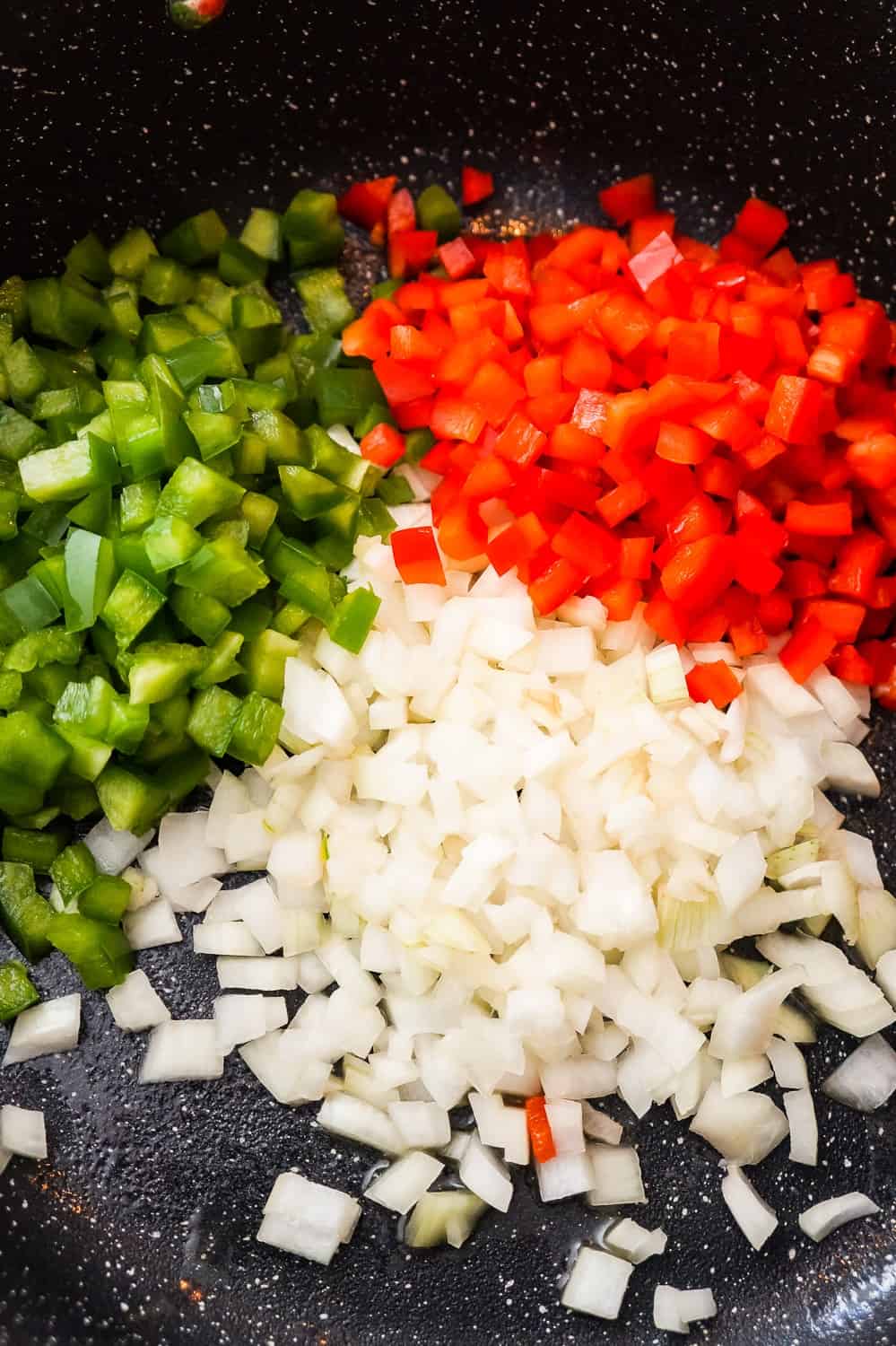 diced onions, diced red peppers and diced green peppers in a saute pan