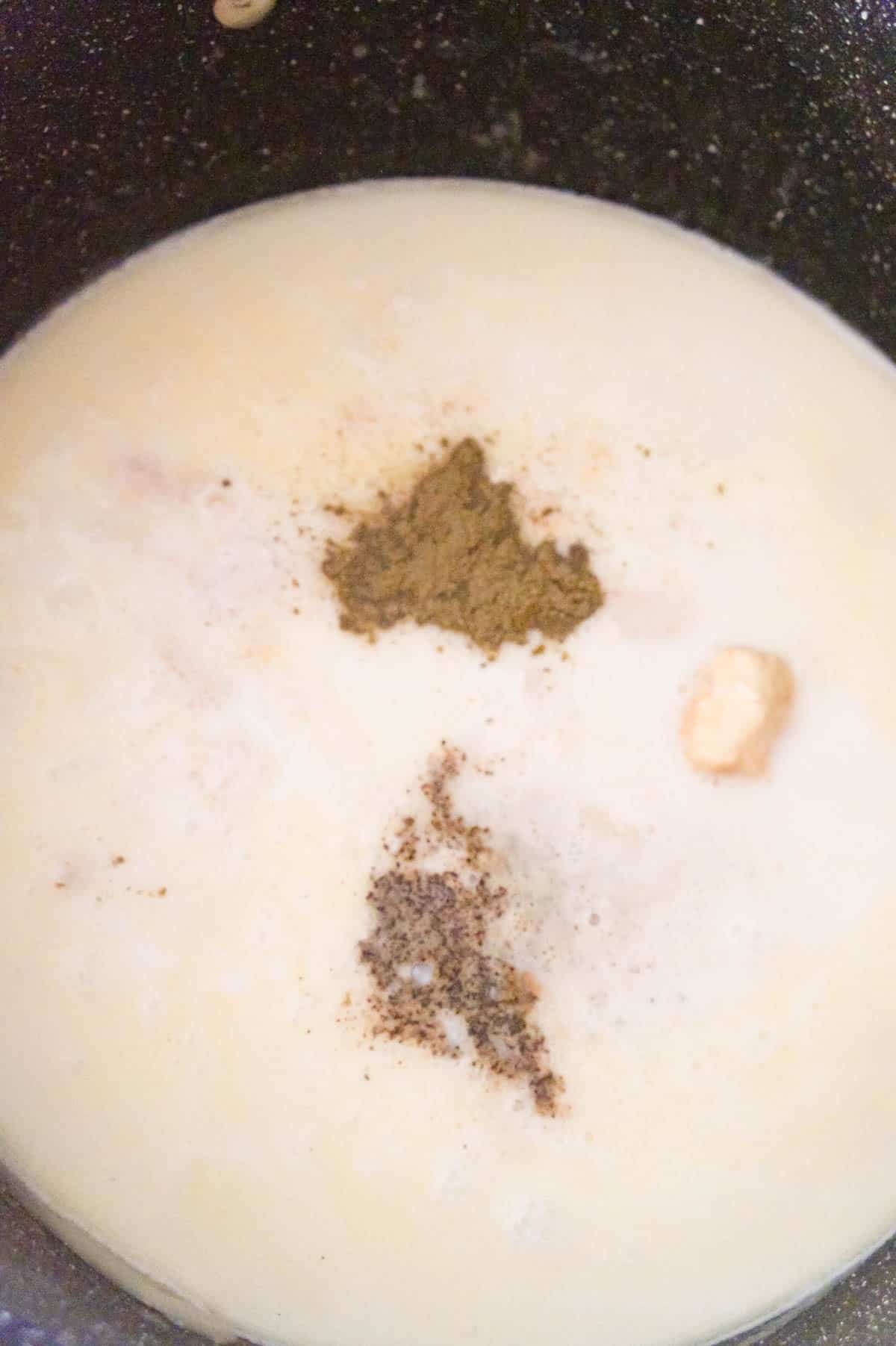 spices added to creamy chicken soup in a large pot