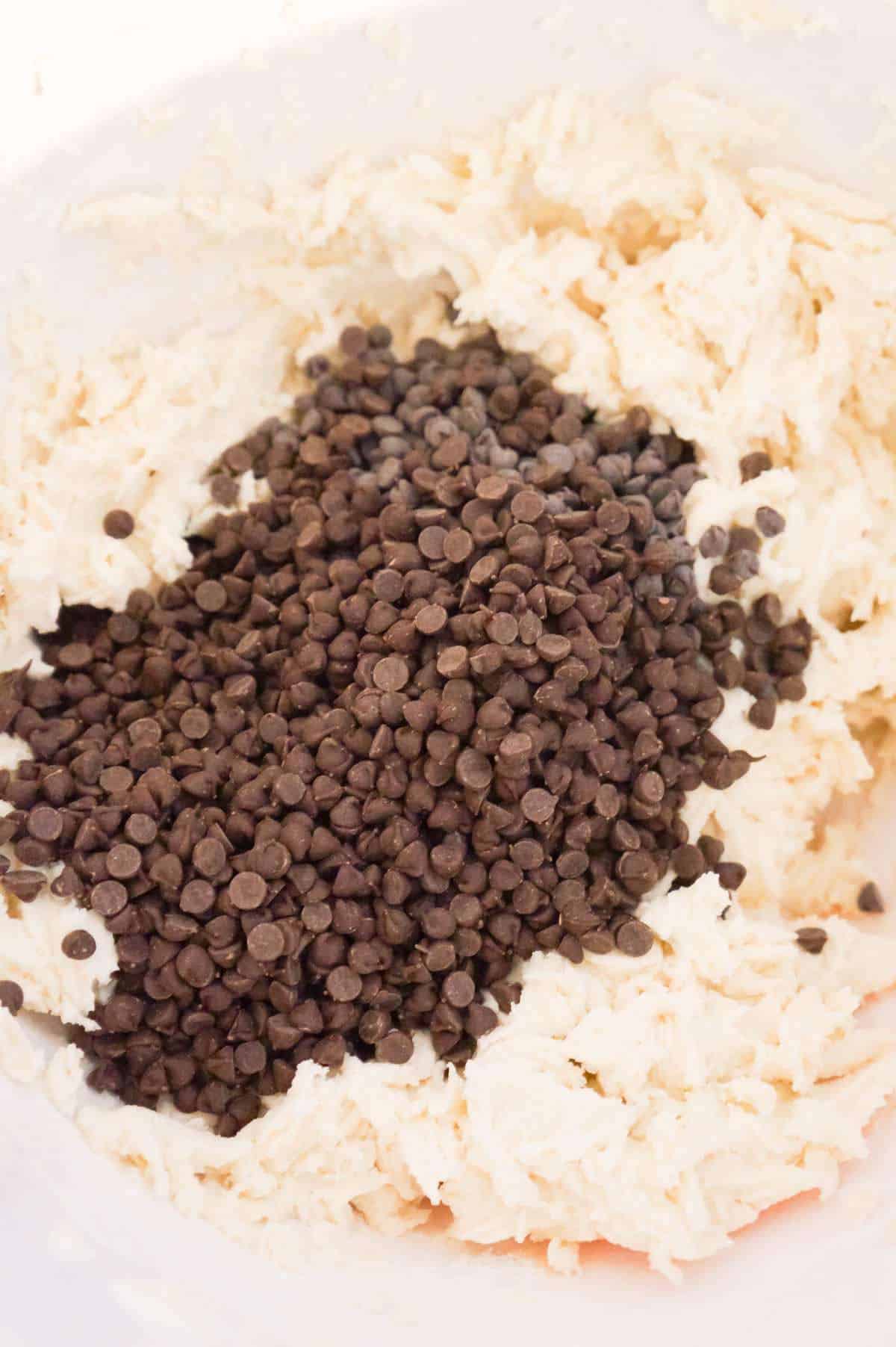 mini chocolate chips on top of shortbread dough in a mixing bowl