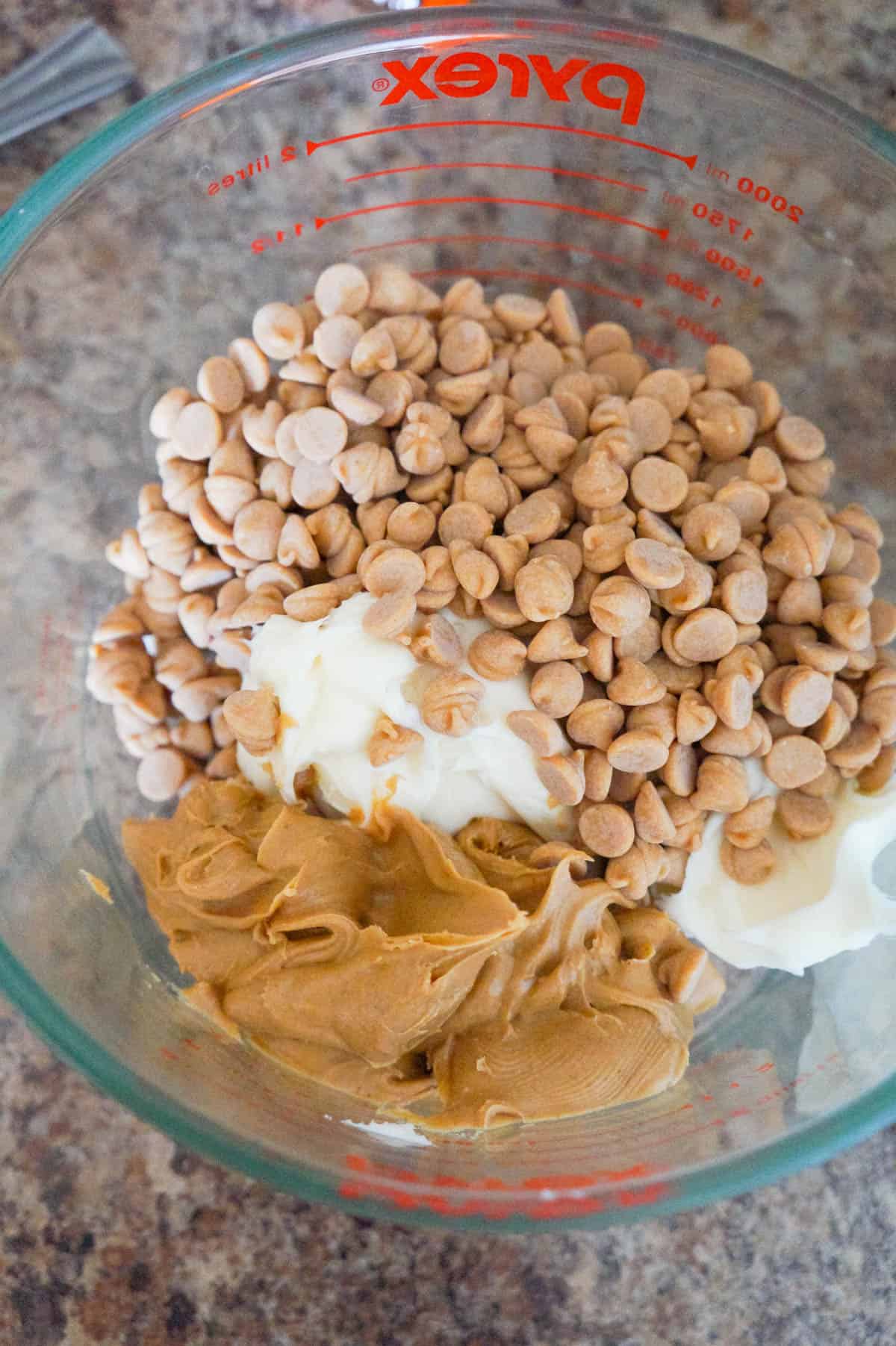 peanut butter baking chips, smooth peanut butter and vanilla frosting in a glass mixing bowl