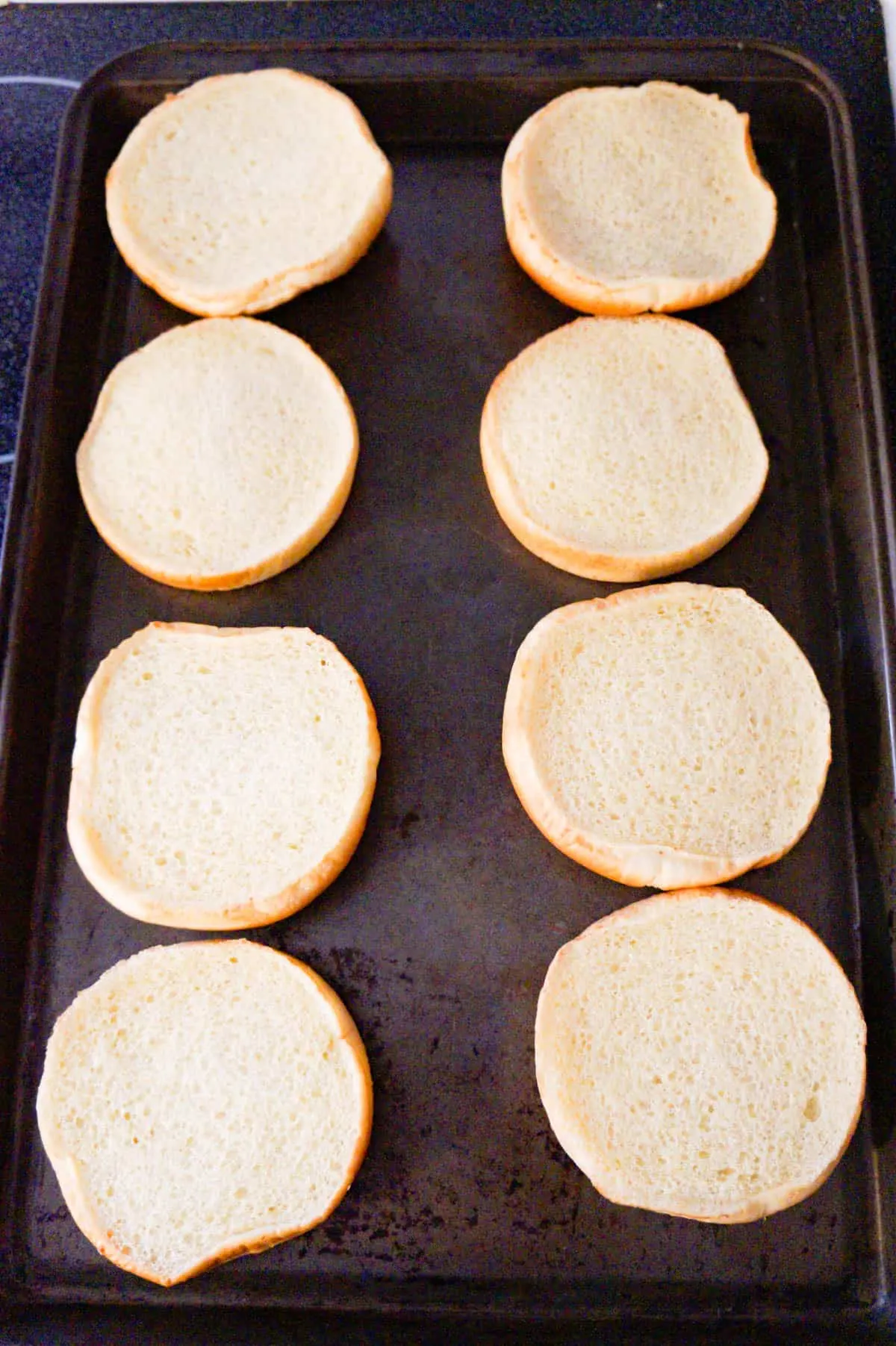 hamburger buns laying on a baking sheet