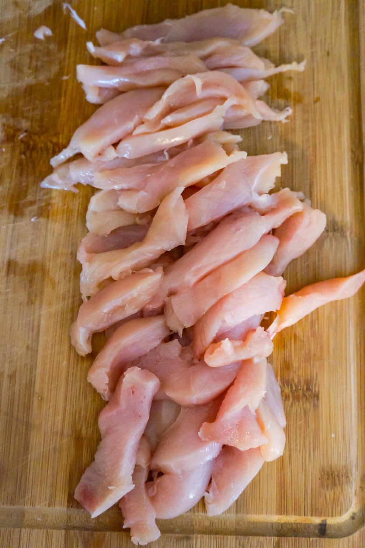 raw chicken breast strips on a cutting board