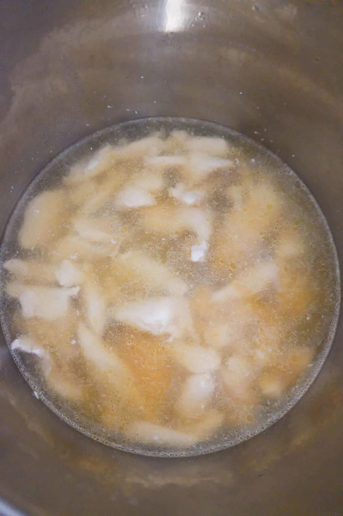 cooked chicken breast strips in chicken broth in an Instant Pot