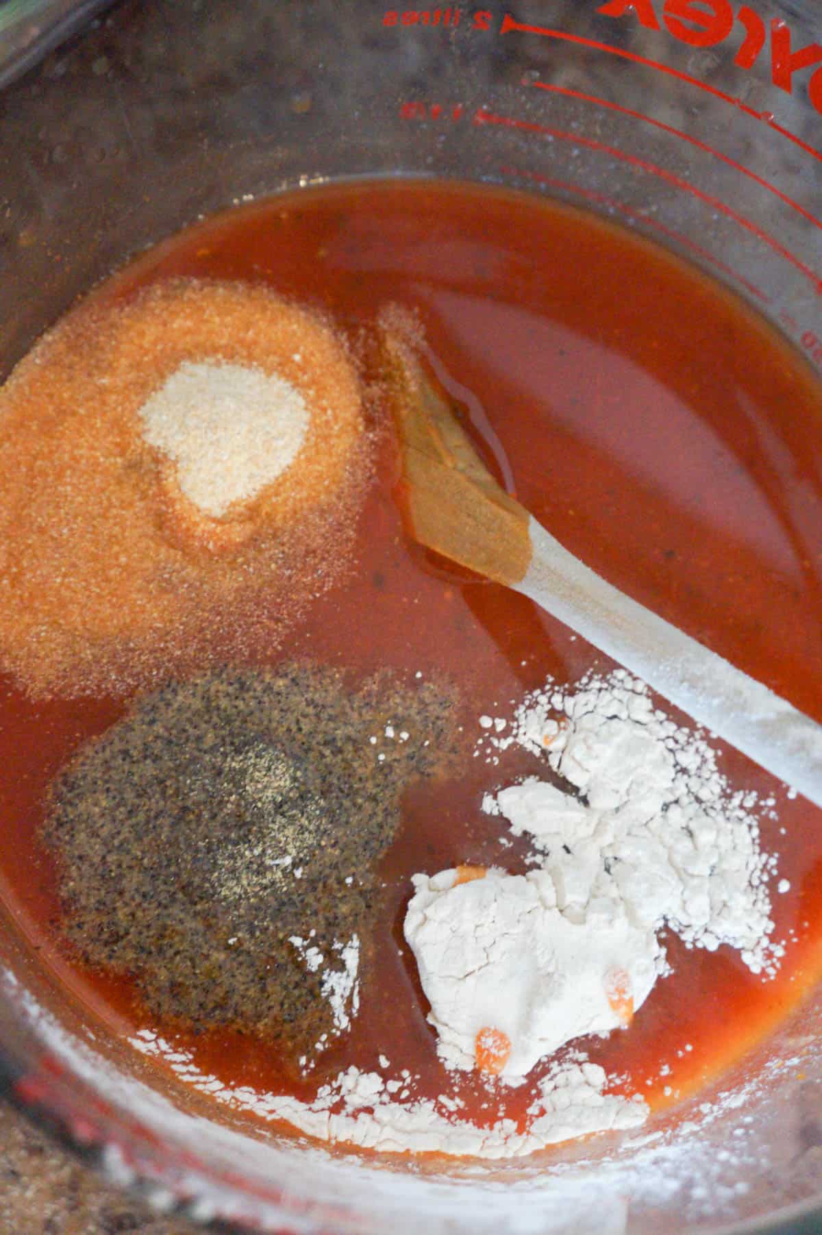 onion powder, galric powder, salt and pepper on top of marinara sauce and water in a large glass measuring cup