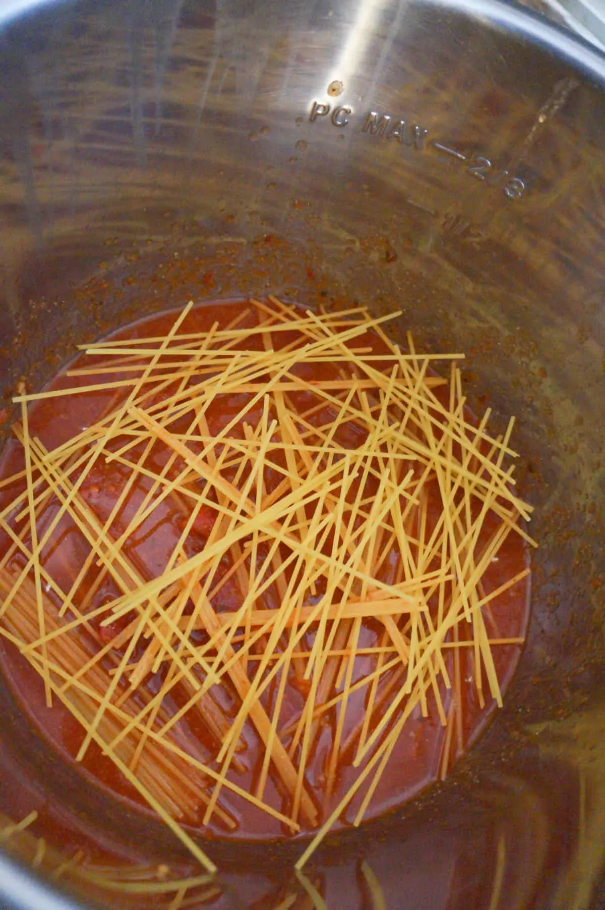 broken spaghetti noodles on top of marinara sauce in an Instant Pot
