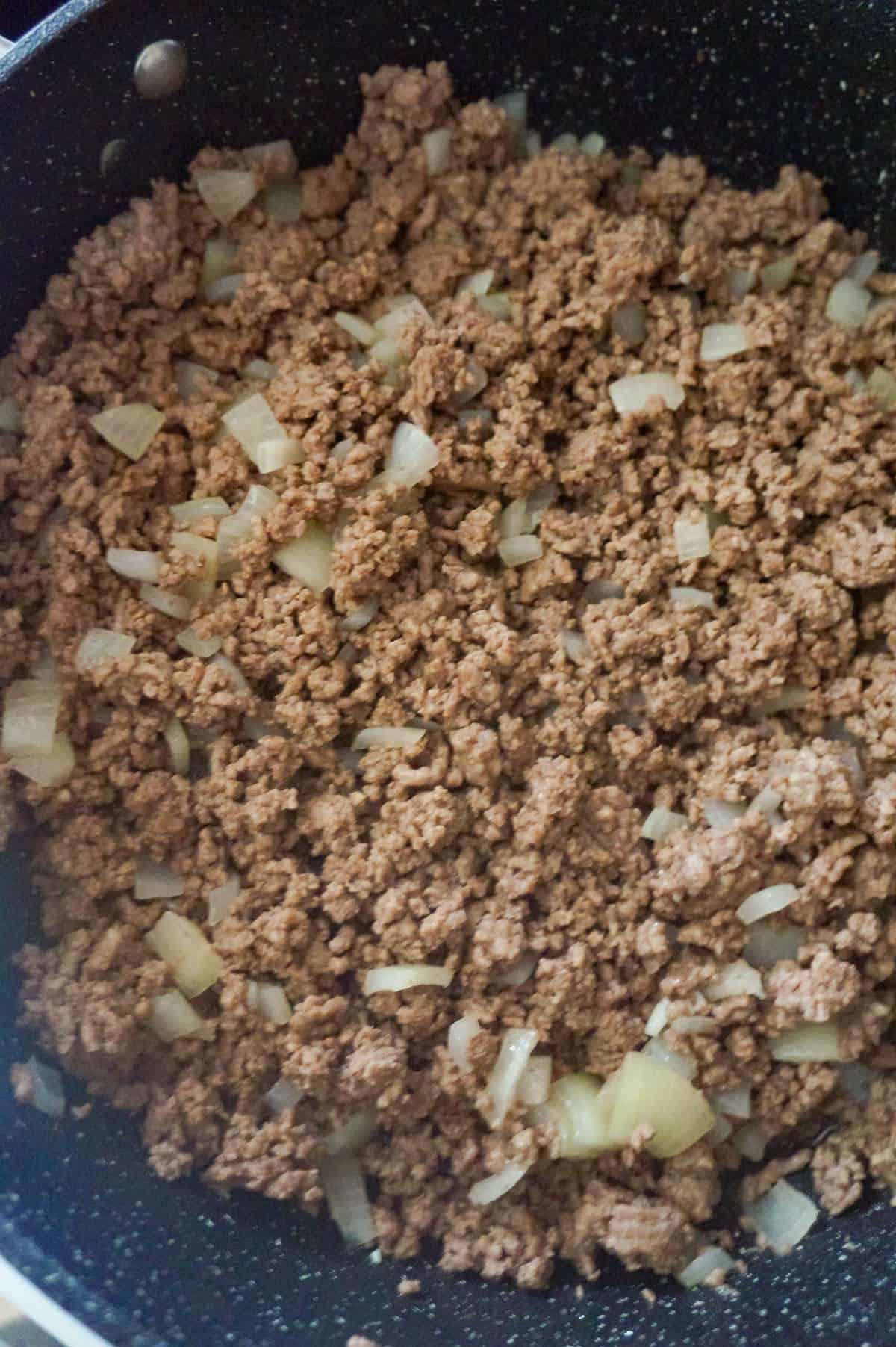 cooked ground beef and diced onions in a saute pan