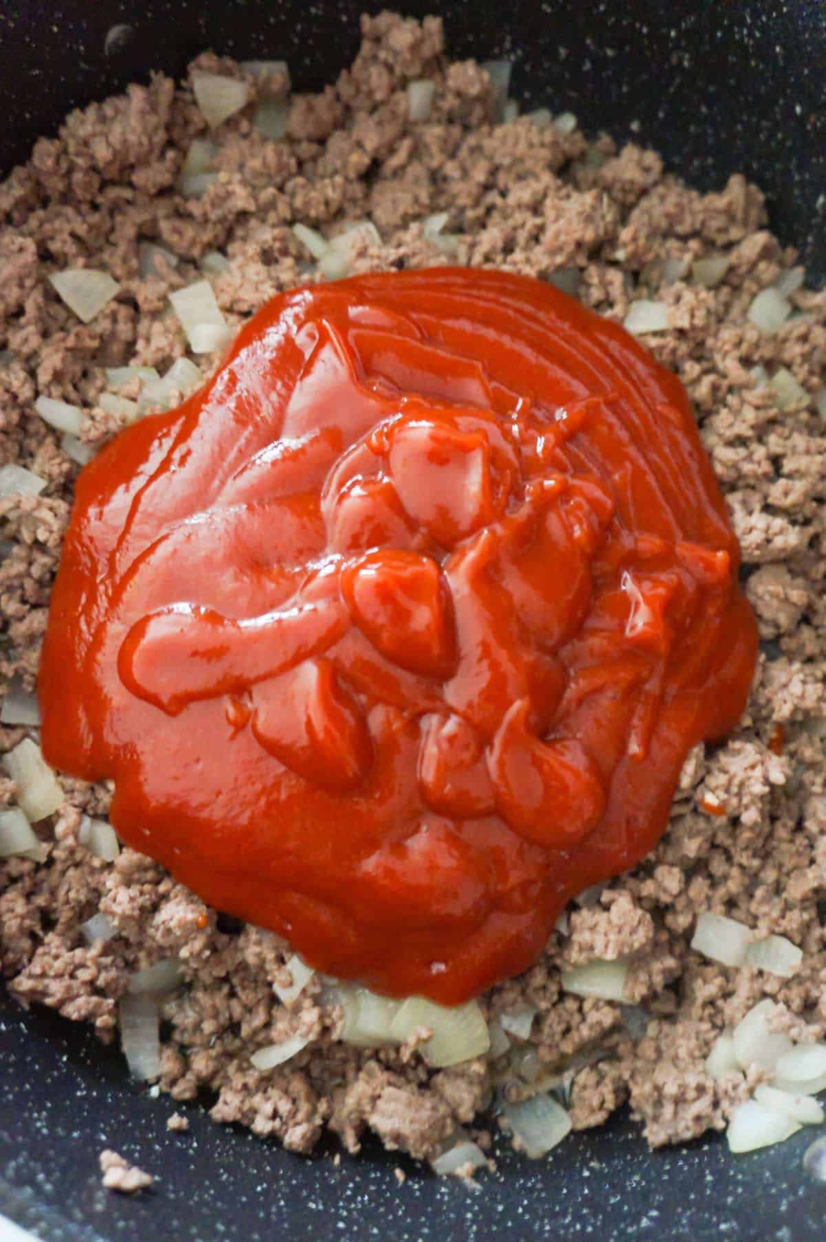 sloppy joe sauce on top of ground beef in a saute pan