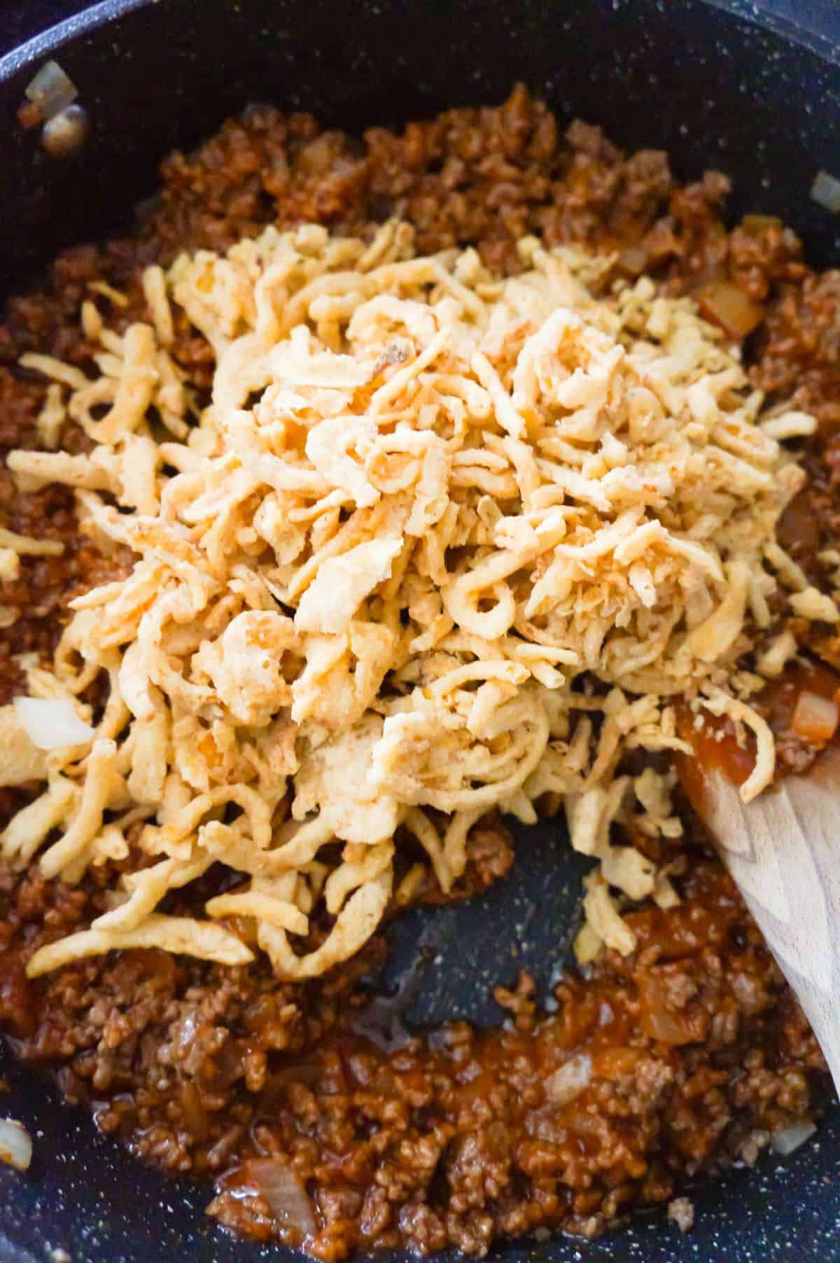 French's fried onions on top of sloppy joe mixture in a saute pan