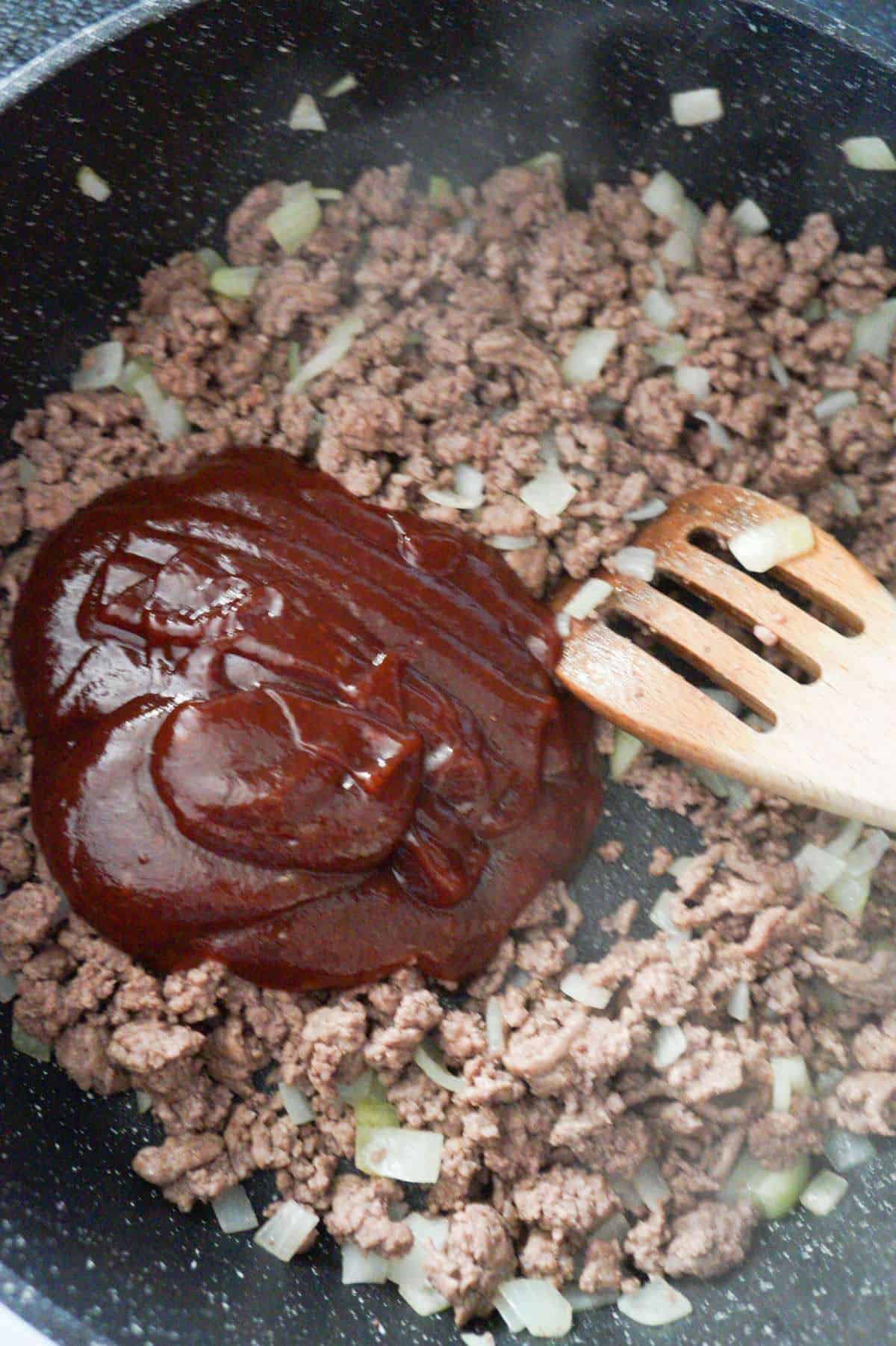 bbq sauce on top of ground beef in a saute pan
