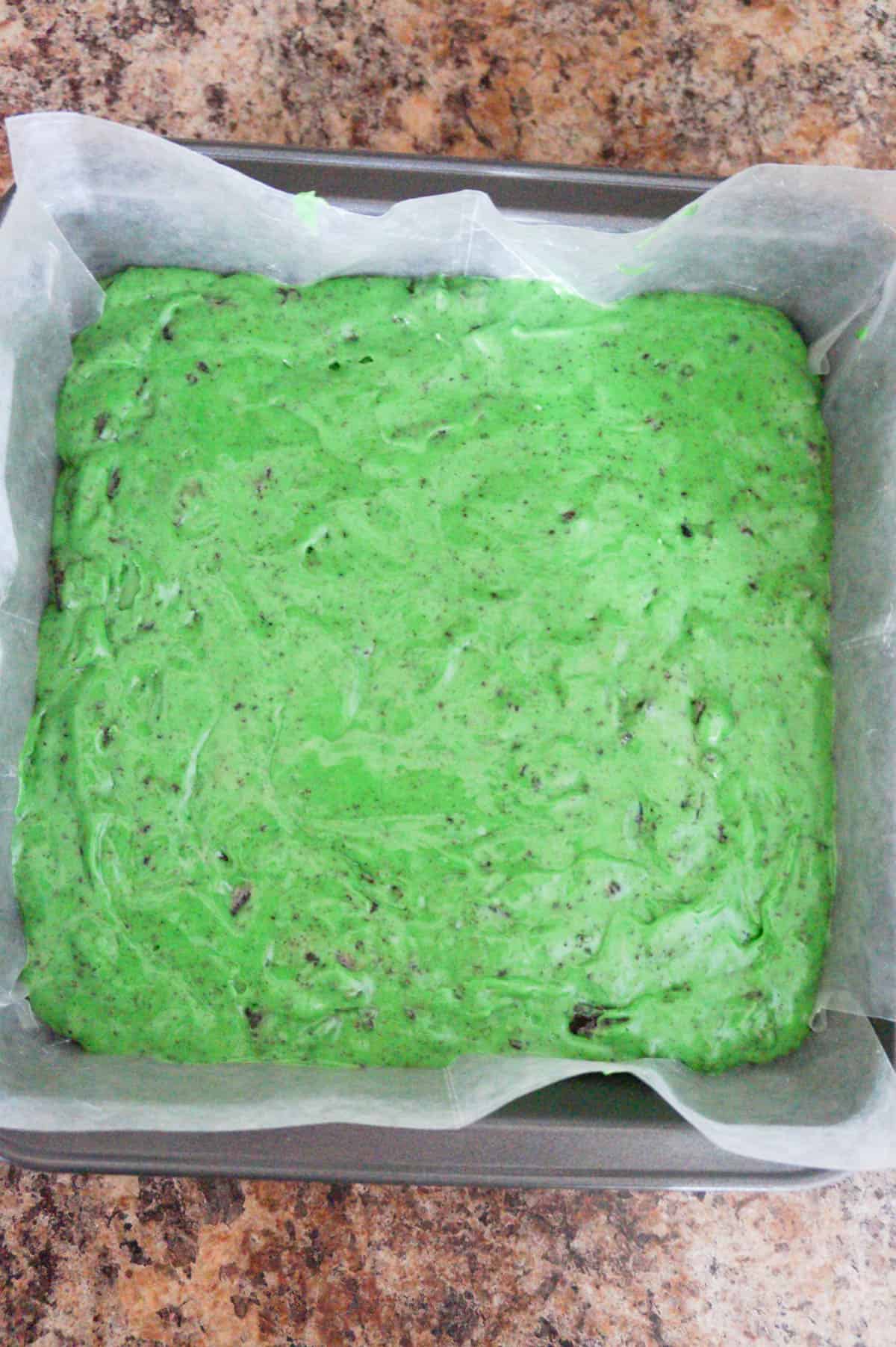green cookies and cream fudge in a wax paper lined baked dish