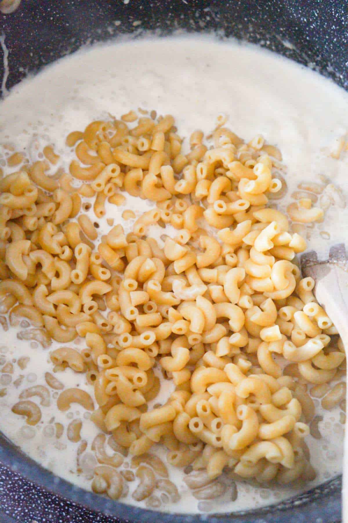 cooked macaroni noodles on top of creamy sauce in a large pot
