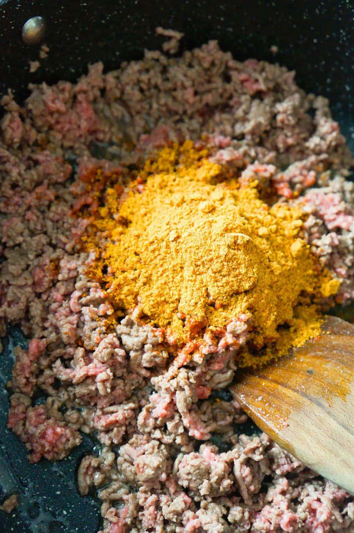 taco seasoning mix on top of ground beef in a saute pan