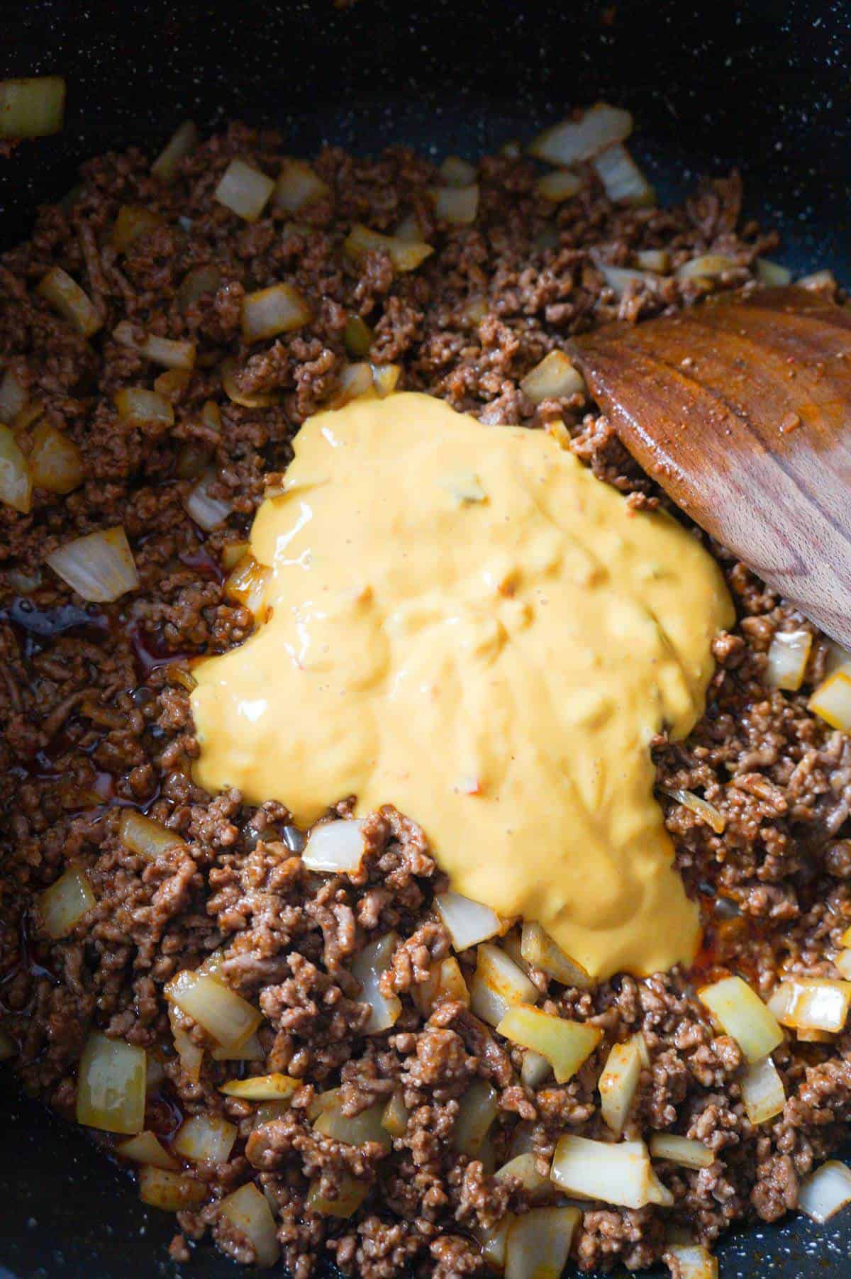 salsa con queso cheese dip on top of cooked ground beef in a saute pan