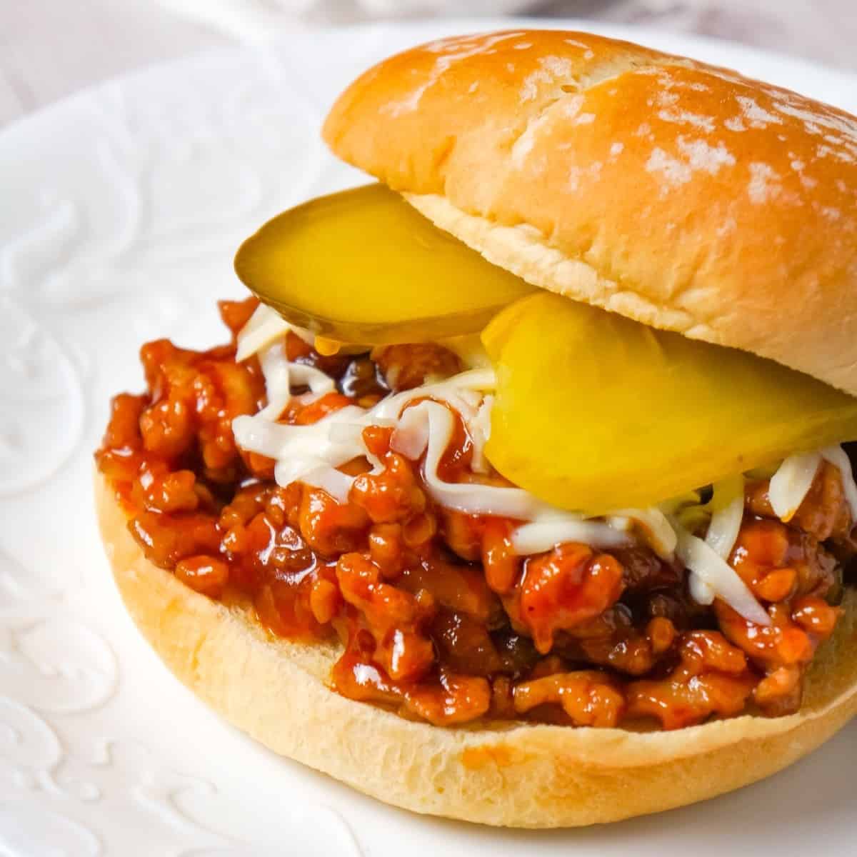 Honey BBQ Chicken Sloppy Joes are an easy weeknight dinner recipe using ground chicken, tossed in honey and BBQ sauce and topped with mozzarella cheese and dill pickles.