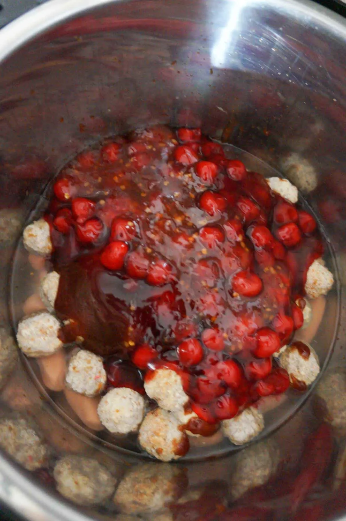 cherry pie filling and bbq sauce on top of frozen meatballs in an Instant Pot