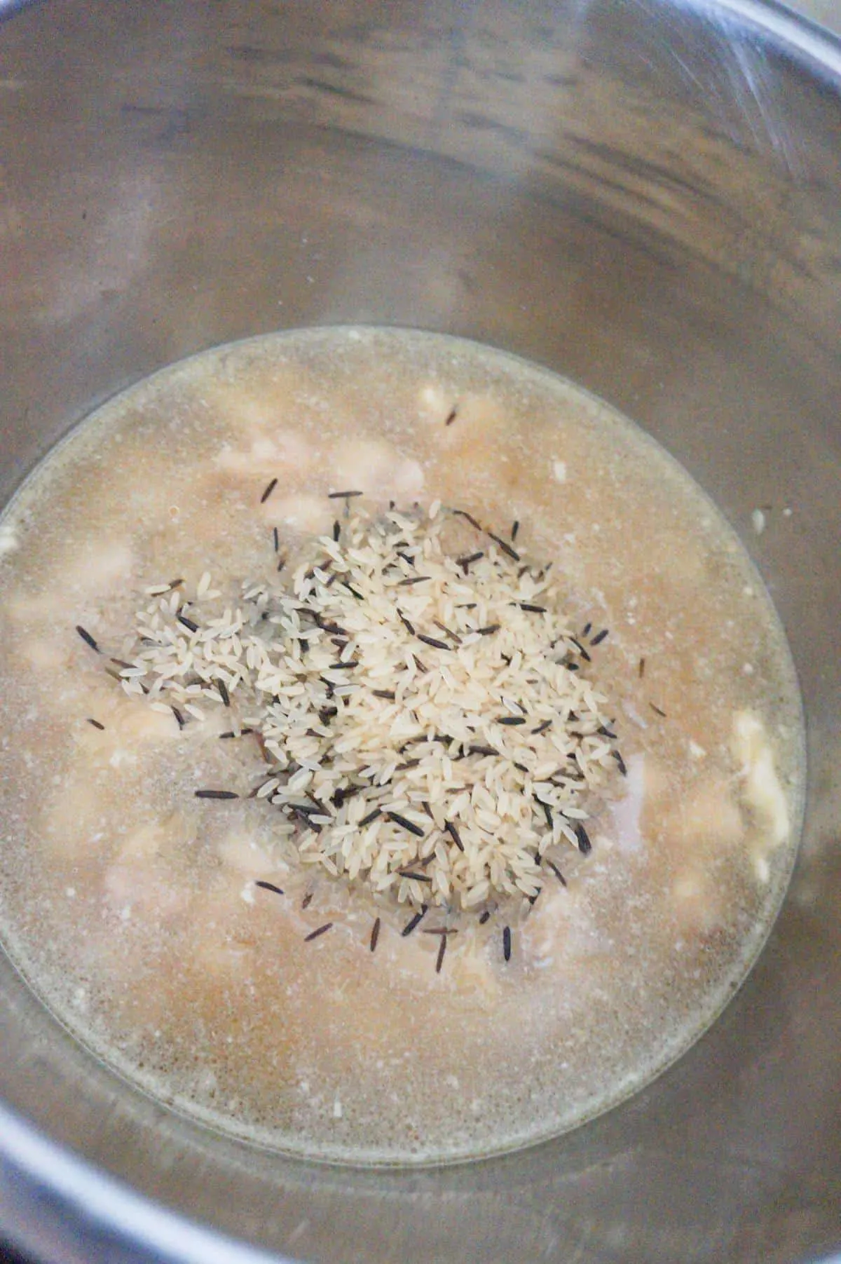 long grain and wild rice blend on top of water and chicken chunks in an Instant Pot