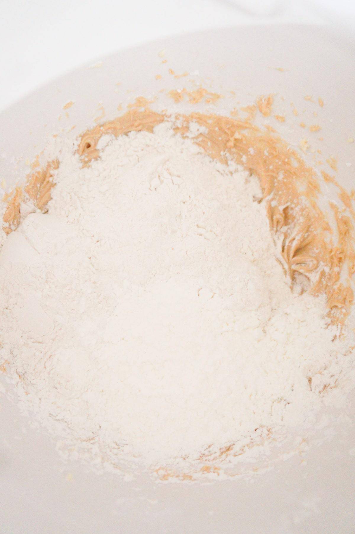 flour and cornstarch on top of creamy butter and peanut butter mixture in a mixing bowl
